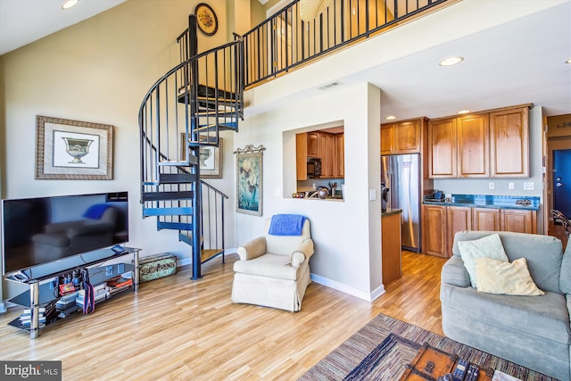living room featuring light wood finished floors, stairs, recessed lighting, baseboards, and a towering ceiling
