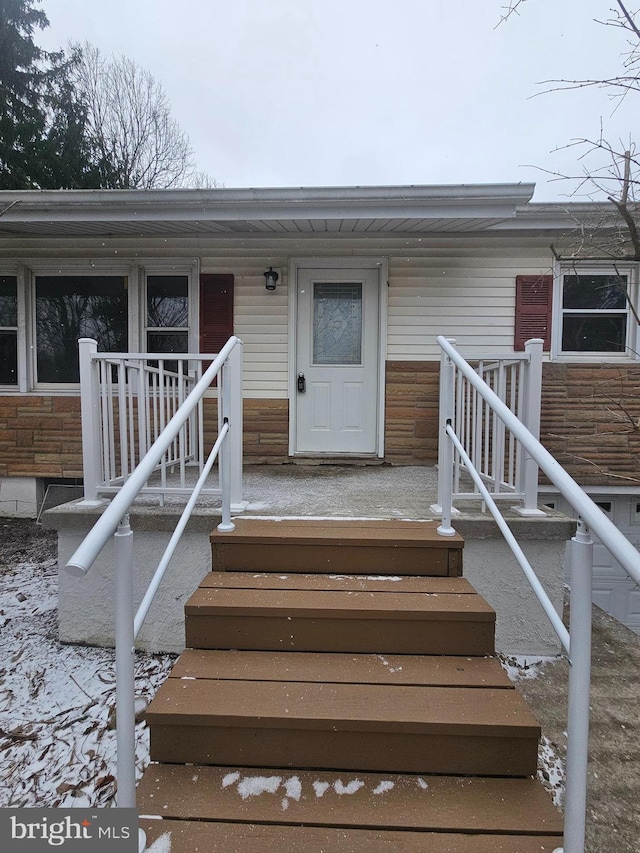 doorway to property with stone siding and covered porch