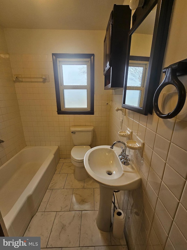 bathroom with a sink, tile walls, and toilet