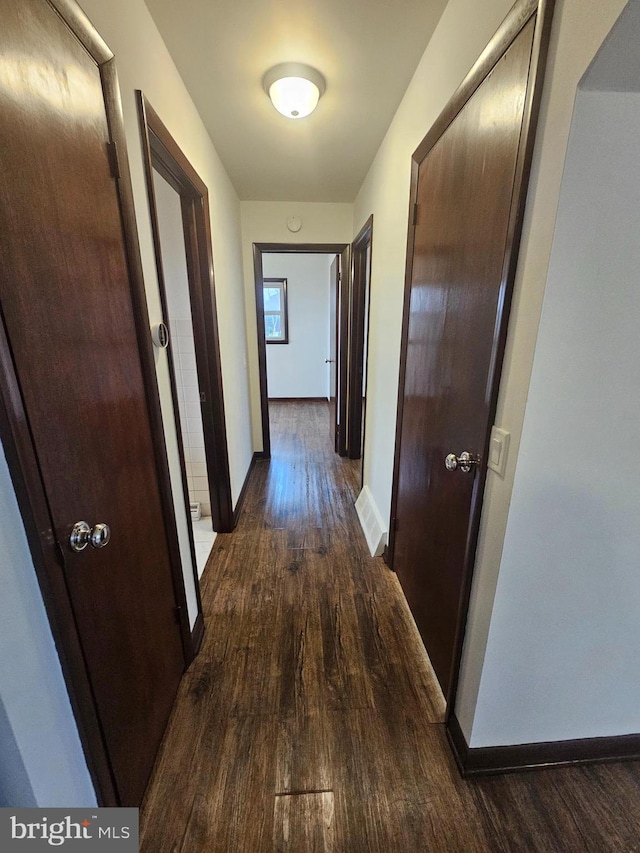 hall with dark wood-style flooring and baseboards