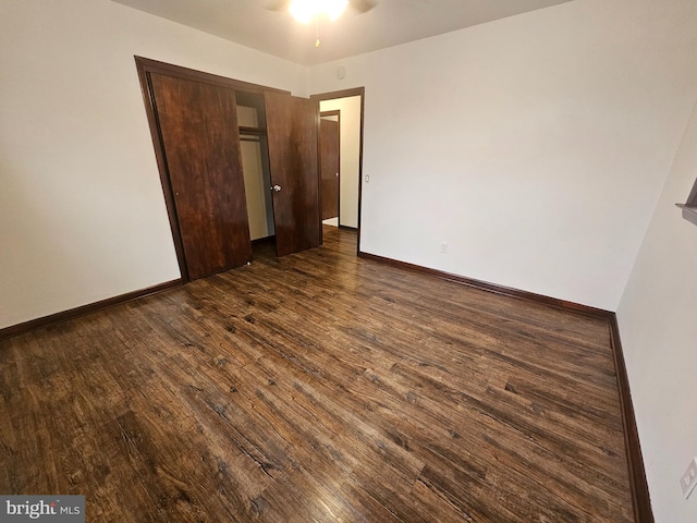 unfurnished bedroom featuring a closet, baseboards, and dark wood-style flooring