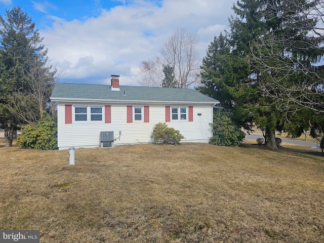 ranch-style house featuring central AC, a front lawn, a chimney, and a shingled roof