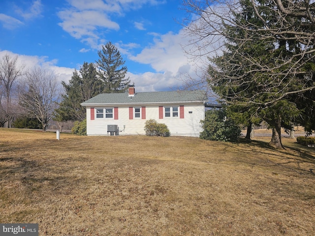 ranch-style house with a front yard, a chimney, and central AC unit