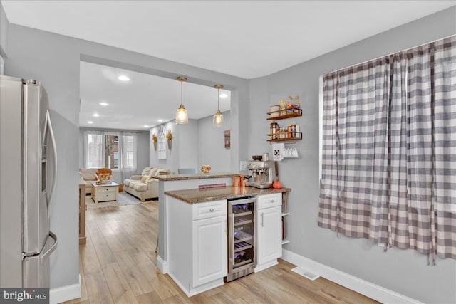 kitchen featuring wine cooler, a peninsula, white cabinetry, stainless steel fridge with ice dispenser, and light wood finished floors