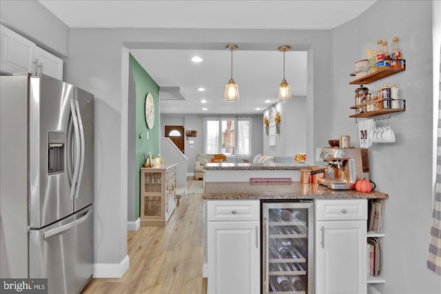 kitchen featuring a peninsula, stainless steel fridge, wine cooler, and white cabinetry