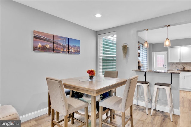 dining space featuring plenty of natural light, light wood-style flooring, and baseboards