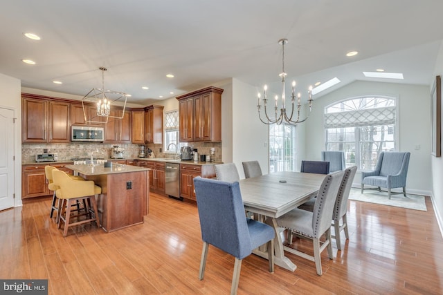 dining room featuring light wood-style floors, a chandelier, vaulted ceiling, and recessed lighting