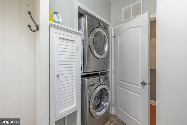 washroom featuring laundry area, tile patterned floors, visible vents, and stacked washer and clothes dryer