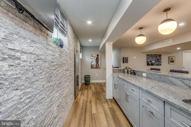 kitchen with light stone counters, recessed lighting, visible vents, hanging light fixtures, and light wood-type flooring