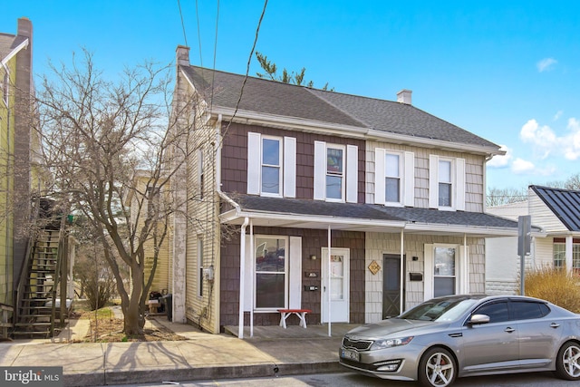 townhome / multi-family property with stairs, a porch, roof with shingles, and a chimney