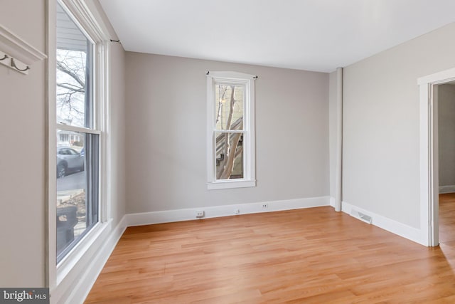 spare room with light wood-style flooring, visible vents, and baseboards