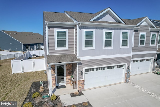 view of front of home with a shingled roof, driveway, an attached garage, and fence