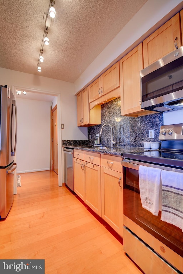 kitchen with light wood-style floors, light brown cabinets, stainless steel appliances, and a sink