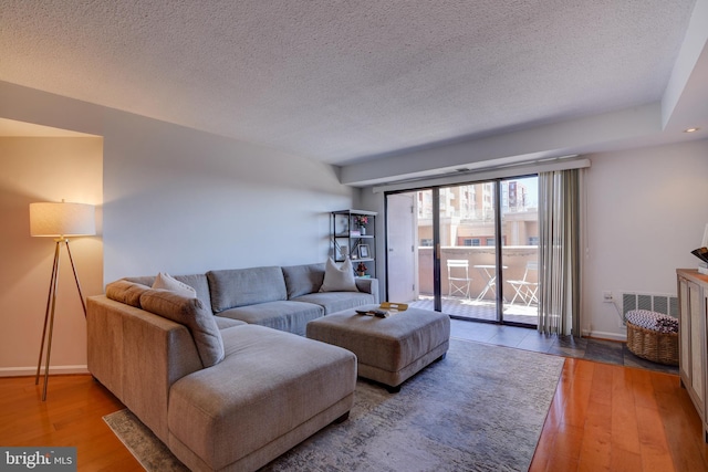 living room featuring a textured ceiling, baseboards, and wood finished floors