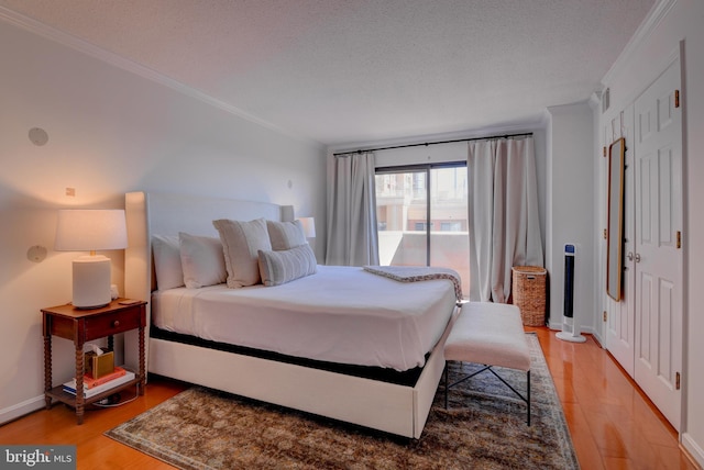 bedroom with a textured ceiling, ornamental molding, and light wood-style floors