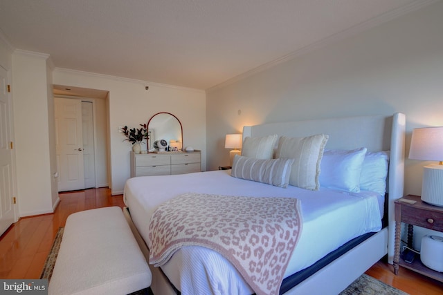 bedroom with light wood-style floors, ornamental molding, and baseboards