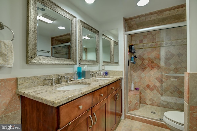 bathroom with a sink, a shower stall, and double vanity