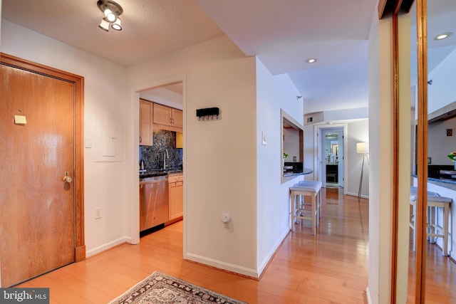 hallway with light wood-style floors, recessed lighting, and baseboards