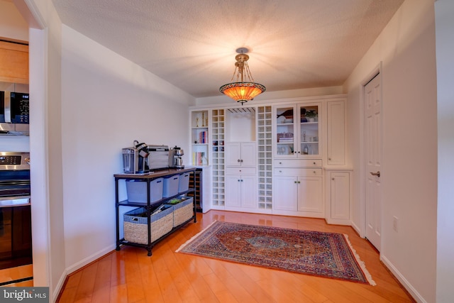 entryway with light wood-style flooring, baseboards, and a textured ceiling