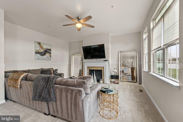 living room featuring visible vents, baseboards, a glass covered fireplace, ceiling fan, and carpet