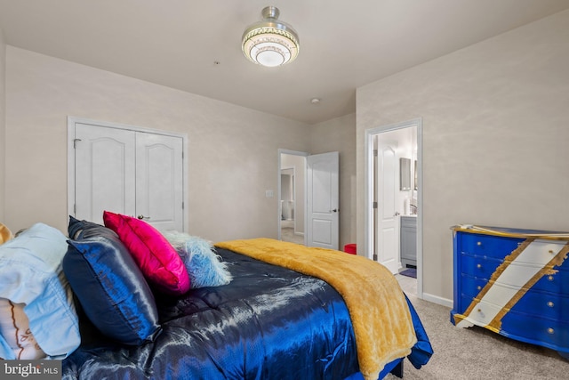 carpeted bedroom featuring a closet, ensuite bath, and baseboards