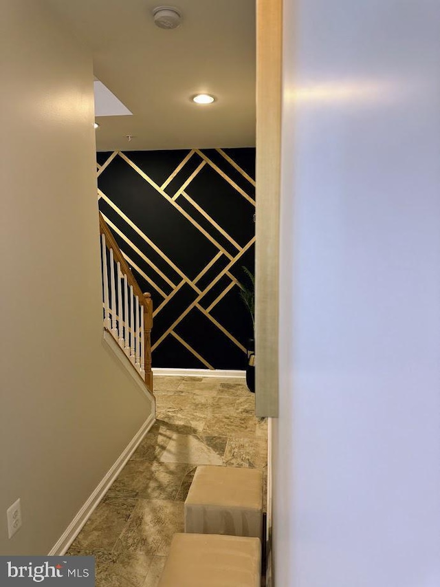 stairway featuring baseboards and stone finish floor