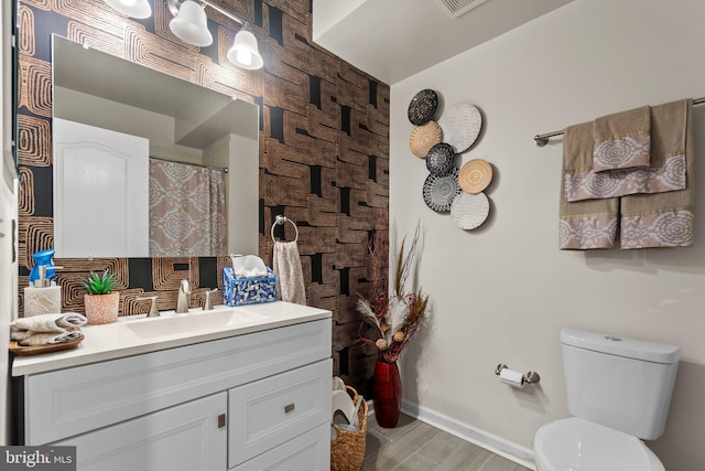 bathroom featuring baseboards, vanity, toilet, and wood finished floors