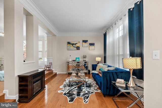 living area with ornate columns, crown molding, baseboards, and wood finished floors