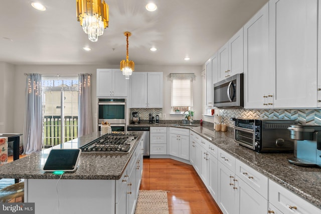 kitchen with stainless steel appliances, a wealth of natural light, light wood-style flooring, and white cabinets