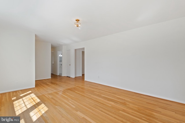 spare room with baseboards and light wood-type flooring