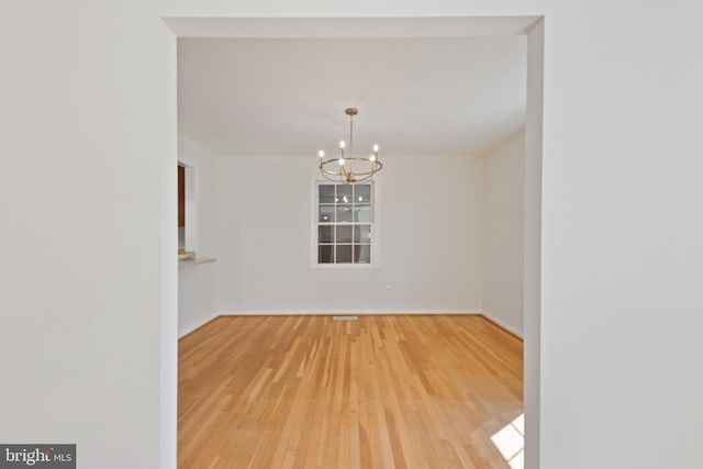 unfurnished room featuring an inviting chandelier and wood finished floors