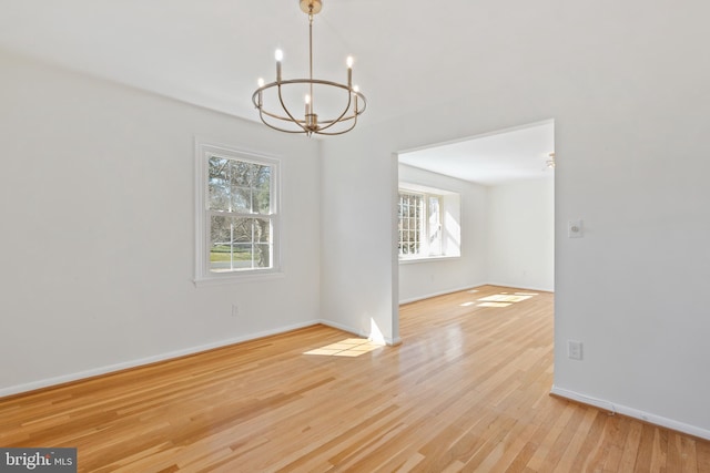 spare room featuring a notable chandelier, baseboards, and wood finished floors