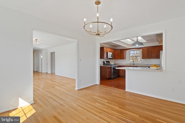 kitchen featuring baseboards, light countertops, light wood-style flooring, appliances with stainless steel finishes, and a sink