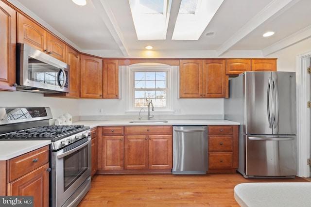 kitchen featuring a sink, appliances with stainless steel finishes, light wood-style flooring, and brown cabinetry