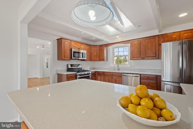 kitchen with beamed ceiling, a sink, recessed lighting, stainless steel appliances, and light countertops