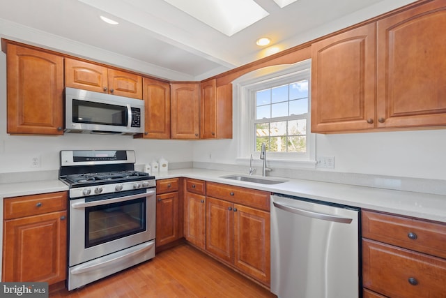 kitchen featuring a sink, light countertops, light wood finished floors, and stainless steel appliances