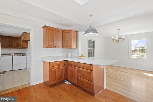 kitchen featuring brown cabinetry, a peninsula, beam ceiling, separate washer and dryer, and light wood-style floors