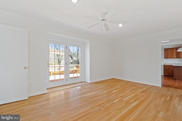 unfurnished living room with crown molding, light wood-style flooring, a ceiling fan, and baseboards