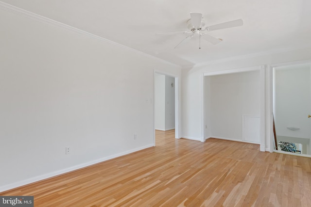 empty room featuring light wood-style flooring, a ceiling fan, baseboards, and ornamental molding