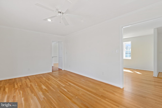 spare room with baseboards, ceiling fan, crown molding, and light wood finished floors