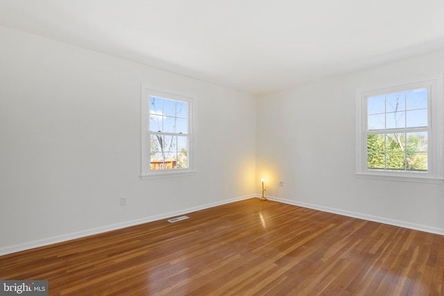 spare room featuring visible vents, baseboards, and hardwood / wood-style flooring