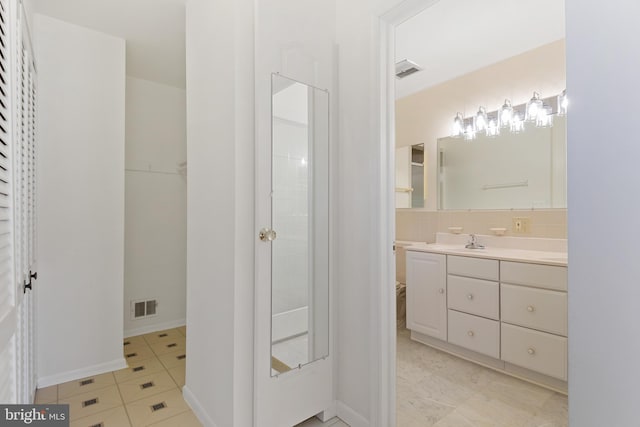 bathroom featuring tile patterned flooring, visible vents, vanity, and walk in shower