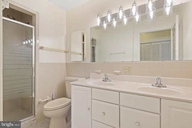 bathroom with a sink, toilet, tile walls, and a shower stall