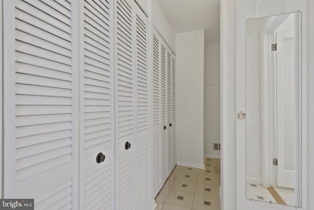 hall featuring light tile patterned floors and visible vents