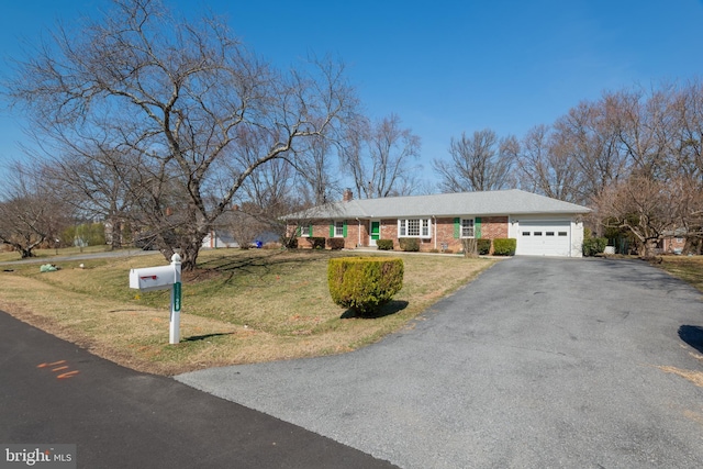 single story home featuring a front yard, driveway, a chimney, a garage, and brick siding