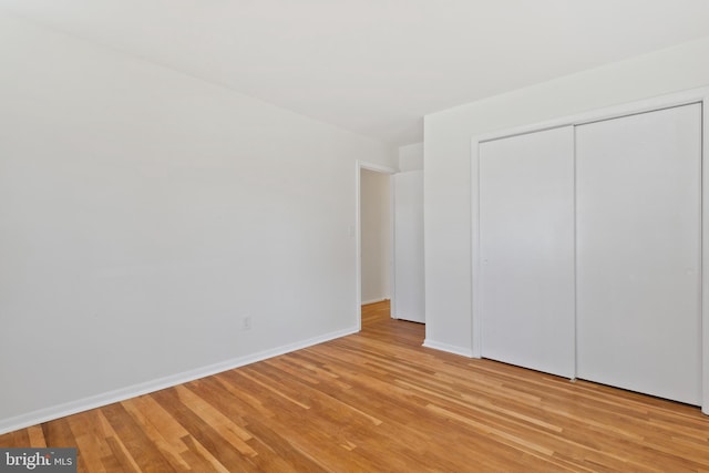 unfurnished bedroom with light wood finished floors, a closet, and baseboards