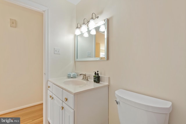 bathroom featuring vanity, toilet, wood finished floors, and baseboards