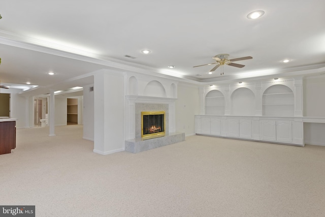 below grade area featuring a ceiling fan, recessed lighting, crown molding, a premium fireplace, and light colored carpet