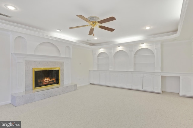 unfurnished living room featuring visible vents, a tray ceiling, carpet floors, a fireplace, and crown molding