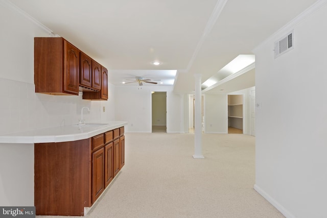 kitchen with visible vents, ornamental molding, a sink, light carpet, and tasteful backsplash